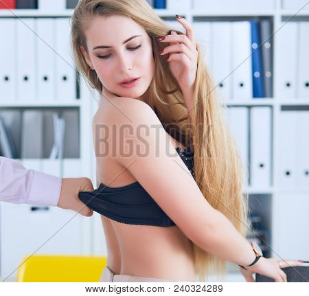 Man's Hand Pulls Bra Out Of The Beauitiful Secretary In Office Background. Flirt Or Harassment Conce