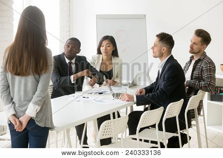 Angry African Boss Pointing On Wristwatch Reprimanding Employee Coming Too Late At Diverse Team Meet