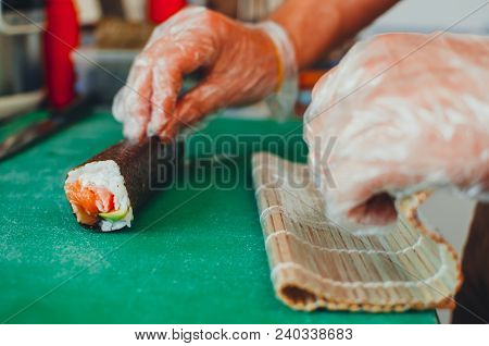 Professional Chef, Chef The Process Of Making Sushi Rolls, Spins Bamboo Mat And Cut Slices