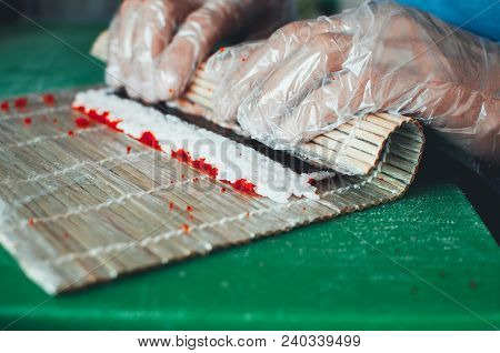 Professional Chef, Chef The Process Of Making Sushi Rolls, Spins Bamboo Mat And Cut Slices