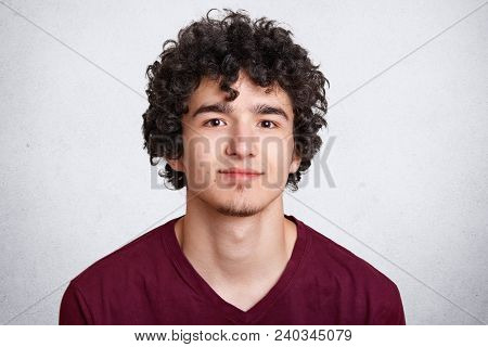 Close Up Shot Of Curly European Male With Little Beard, Wears Casual Sweater, Isolated Over White Co