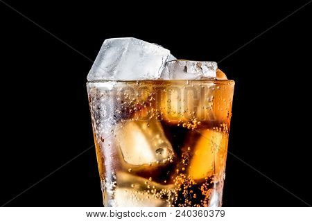 Stream Of Soda Being Pouring Into A Glass With Soda And Ice Cube On Black Background, Closeup Textur