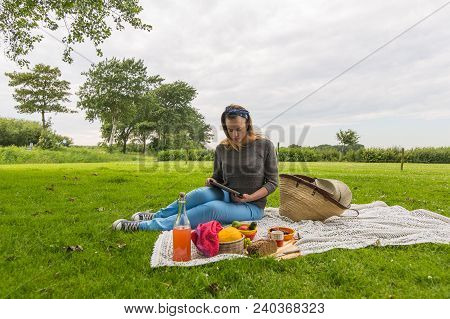Young Attractive Woman With Tablet Pc At A Picnic On The Nature In The Countryside