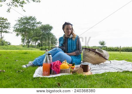 Young Woman With Tablet Pc Looking At Camera At A Picnic On The Nature In The Countryside