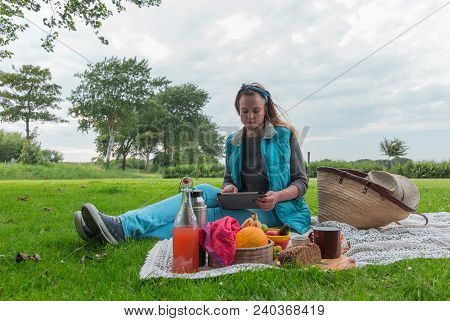 Young Woman With Tablet Pc At A Picnic On The Nature In The Countryside