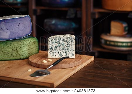 Cheese Heads With Slices And Knives Lie On A Wooden Board With An Interior