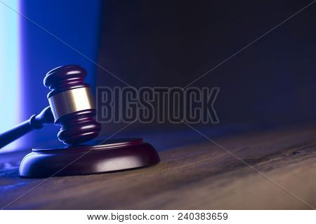Law theme. Mallet of the judge on wooden desk and blue background. Place for text.