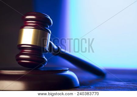 Law theme. Mallet of the judge on wooden desk and blue background. Place for text.