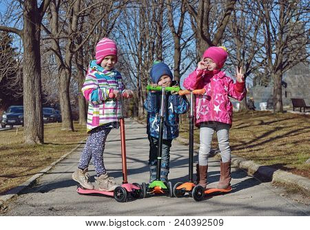 Treee Children On The Scooters In The Park