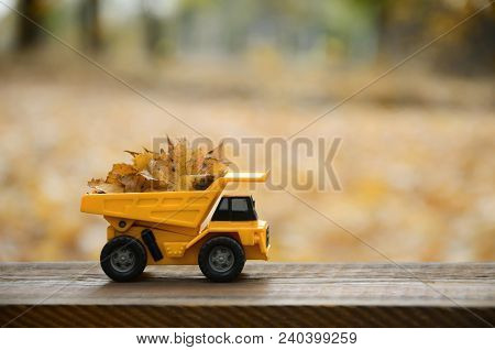 The Concept Of Seasonal Harvesting Of Autumn Fallen Leaves Is Depicted In The Form Of A Toy Yellow T