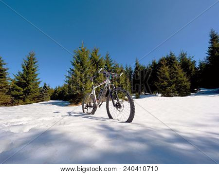 Close Wide View To Mountain Bike Stays In Snow. Winter Snowy Mountains With Road Between Trees.