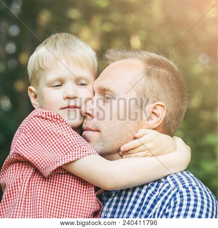 Father And Little Son Hugging And Smiling In The Garden. Masculinity Concept.