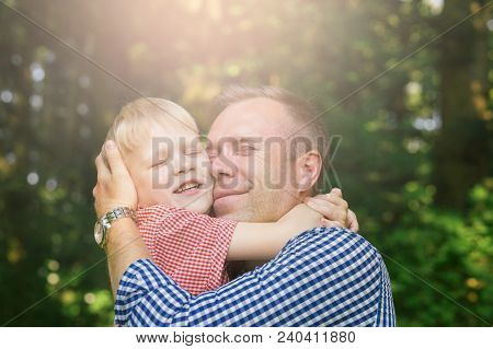 Father And Son Hugging And Smiling In The Garden. Masculinity Concept.