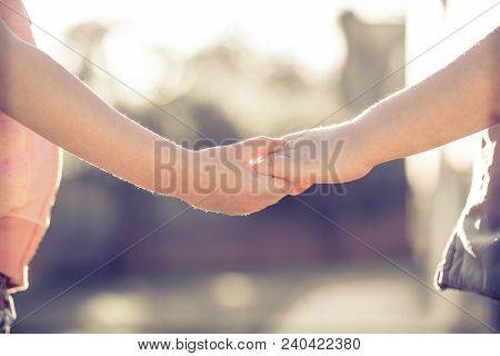 Little Girl And Boy Hold Hands Close-up, Against The Backdrop Of A Green Garden.