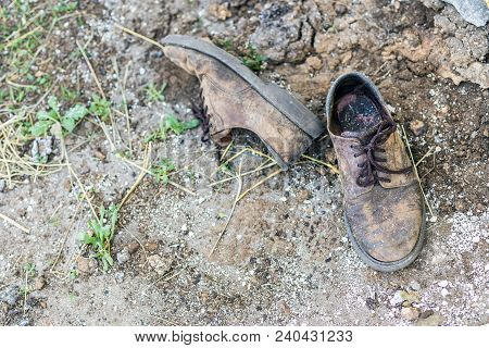 Pair Of Old Dirty Used Shoes.  Abandoned Discarded Boots Laying In Dust On Ground. Poverty Or Beggar