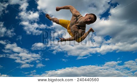 Tricking On Street. Martial Arts. Man Performs Somersault Ahead Barefoot. Shooted From Bottom Foresh