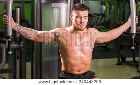 Mixed Race Fitness Man Is Working Out On Butterfly Machine In Gym.