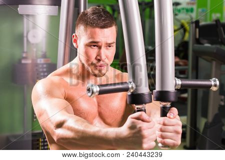Mixed Race Man Is Working Out On Butterfly Machine In Gym.