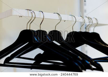 Empty Wooden Clothes Hangers In Empty Black Cloakroom,