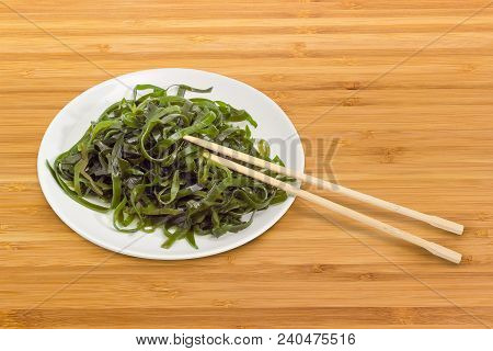 Salad Of Marinated Sliced Laminaria With Vegetable Oil And Spices On The White Dish With Bamboo Chop