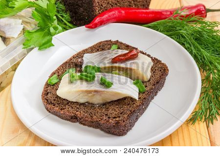 Open Sandwich Made Of Brown Bread And Slices Of Fillet Of Pickled Atlantic Herring On A Saucer Among