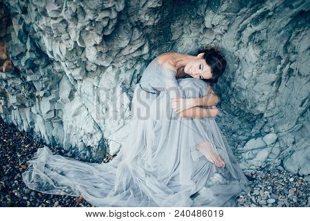 Very Beautiful Brunette Girl In A Long Gray Gown Of Lace And Tulle, The Veil Sits With His Head Bowe