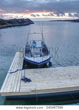 Fishing Boat Anchored In Silent Bay, Evening Sun At Horizon.  Small Ship With Fishing Rods At Wooden