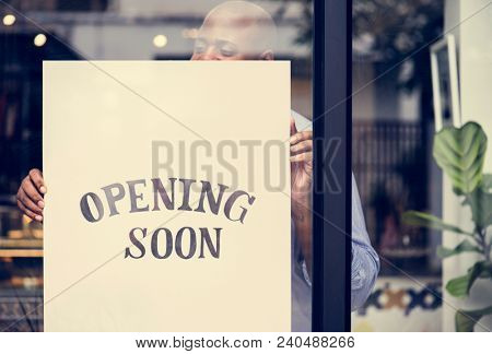 Man putting on store opening soon sign