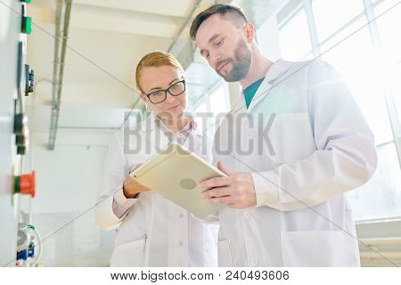 Group Of Concentrated Technologists Wearing White Coats Taking Necessary Notes On Digital Tablet Aft
