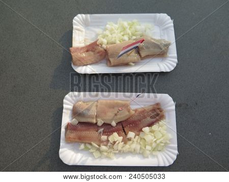 Paper Plates With Newly Cought Herrings With Onions In Dutch Fishing Village