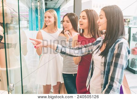 Girls Are Standing At The Showcase Of Lingerie Store And Looking At Maneken With Interest. Brunette 