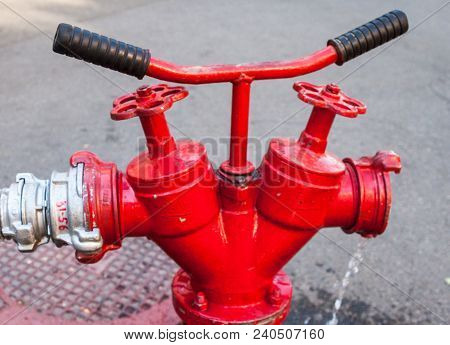 Red Fire Hydrant With Connected Hose. Close-up.