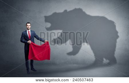 Businessman standing with red cloth in his hand and big bear shadow on his background