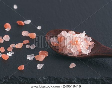 Himalayan Pink Salt In Spoon On Black Stone Background. Copy Space