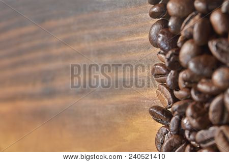 Coffee Beans Lie On The Right On A Light Wooden Background. Wallpaper