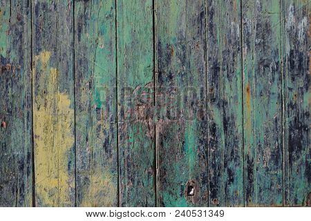 Wooden door background, colorful and peeled. Timeworn entrance provides safety and privacy. Close up view with details.
