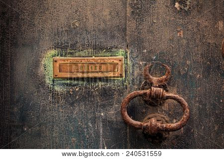 Wooden brown door background with rusty letterbox and doorknob. Timeworn closed entrance, close up view with details.