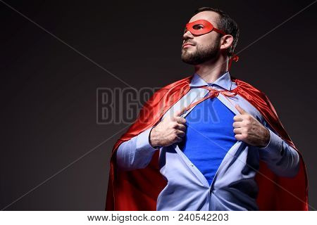 Handsome Super Businessman In Mask And Cape Showing Blue Shirt And Looking Away Isolated On Black