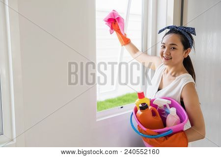Beautiful Asian Woman Or Housewife Using Pink Microfiber Cloth To Cleansing Window Or Mirrror Of New