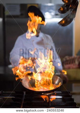 Chef cooking and doing flambe on food in restaurant kitchen