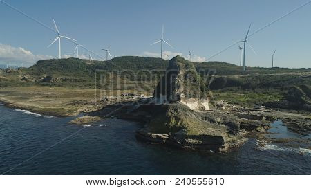 Natural Rock Formation Of Limestone Stone On The Coast With Windmills For Electric Power Production.