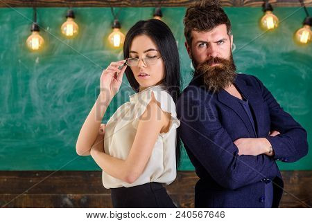 Man With Beard And Teacher In Eyeglasses Stand Back To Back, Chalkboard On Background. Teamwork Conc
