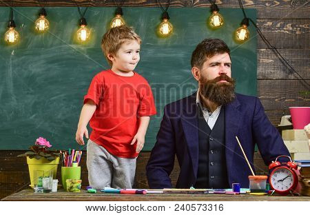 Kid With Funny Face Standing By His Father. Daddy And Son Looking Out In One Direction. Man In Smart