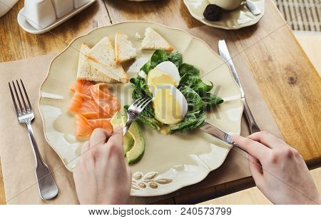Healthy Breakfast - Poached Eggs With Smoked Salmon, Avocado, Spinach And Crusty Baguette. Woman Eng