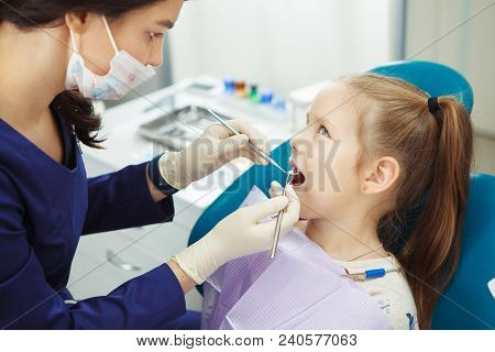 Child Lies In Comfortable Dentis Chair And Goes Through Procedure Without Fear While Female Doctor I