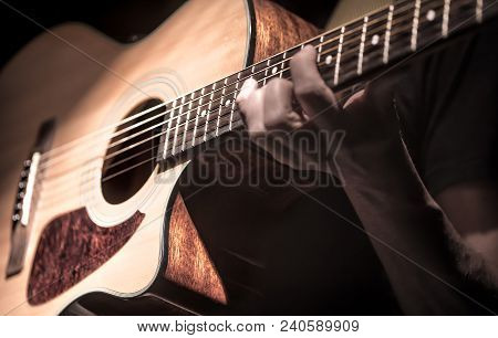Man Playing Acoustic Guitar On Dark Background, Guitar Closeup. A Musical Concept.