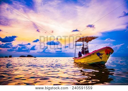 The Boat Is Anchored At Sunset In Calm Weather, During A Sunset