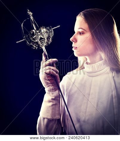 Fencing sport for women fencer. Fia female athlete in fight epee competition. Large group fans on tribunes with lens flare illumination. Girl warrior from Middle Ages.
