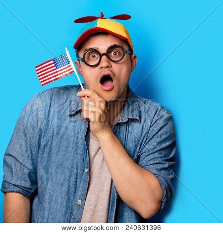 Young Nerd Man With Noob Hat Holding An American Flag On Blue Background