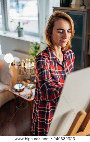 Female Artist Working On Painting In Studio